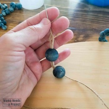 blue wooden beads threaded through jute for diy hanging plant shelf