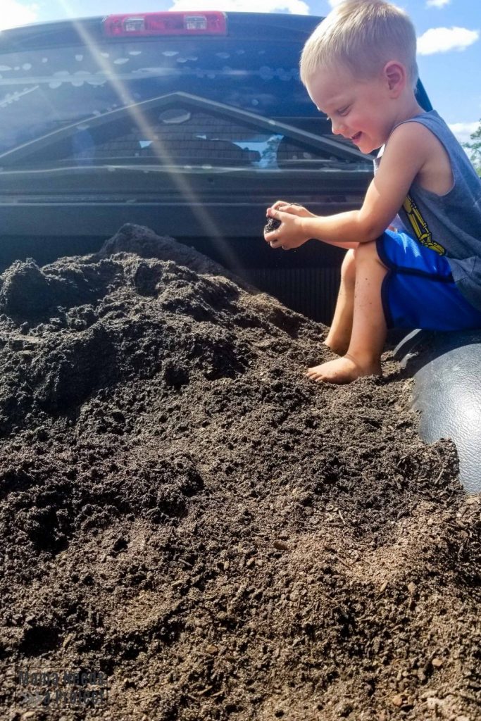 toddler on pile of soil in truck bed
