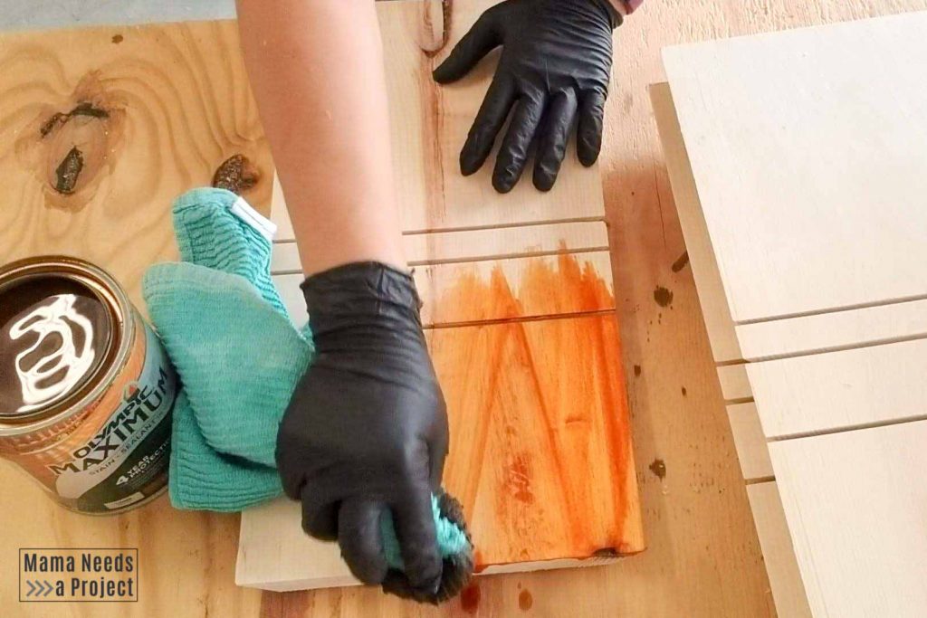 applying stain with a rag to the sides of the diy modern wood planter