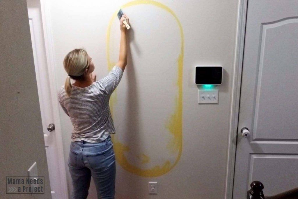 woman painting a large oval on the wall