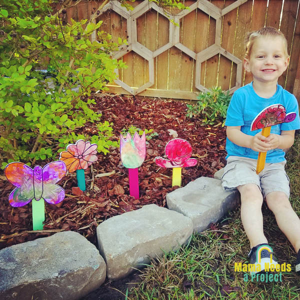 Child holding DIY wood garden signs in a garden