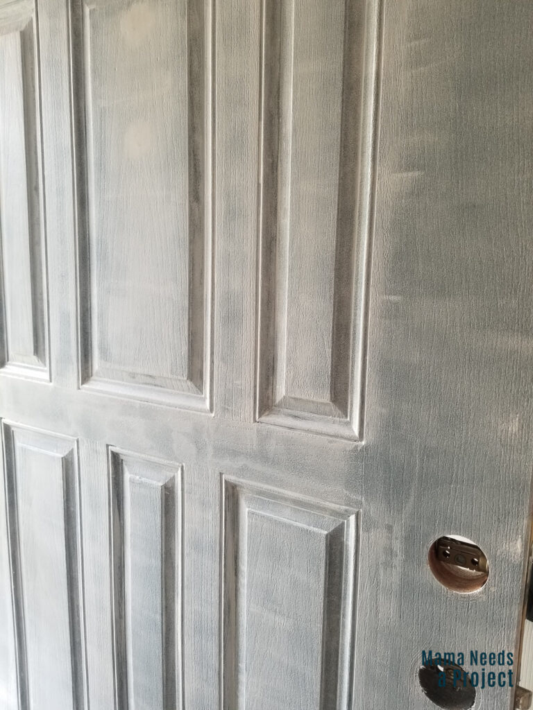 front door painted with one coat of primer, green paint showing through primer