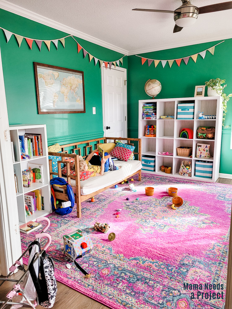 playroom with toys, couch, pink rug and child on couch, green walls with painted trim
